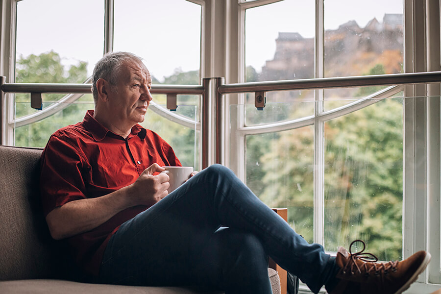 James Sutherland sat looking out the of window in a cafe. Edinburgh castle is in the background.