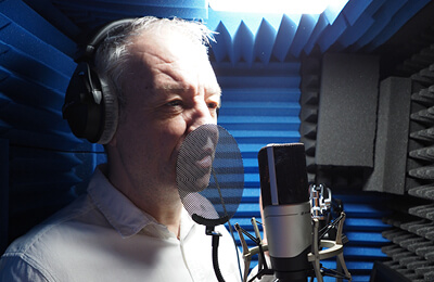 James Sutherland in his home studio talking into a microphone.